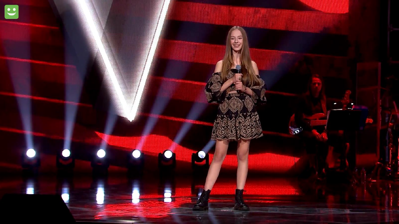 Hania Sztachańska stojąca na scenie programu. Dziewczyna kest uśmiechnięta, w ręku trzyma mikrofon.