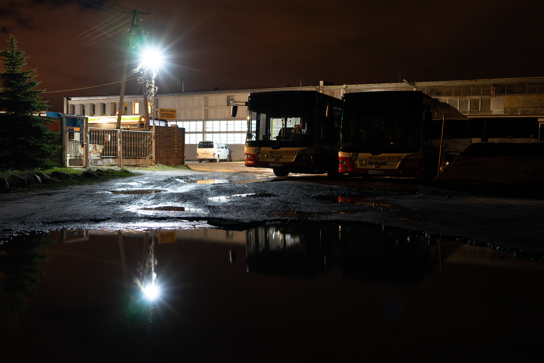 Na zdjęciu dawna baza Rokbusu wieczorem. Na zewnątrz dwa autobusy. Widok rozświetla latarnia. Autor: Piot Surmiński.