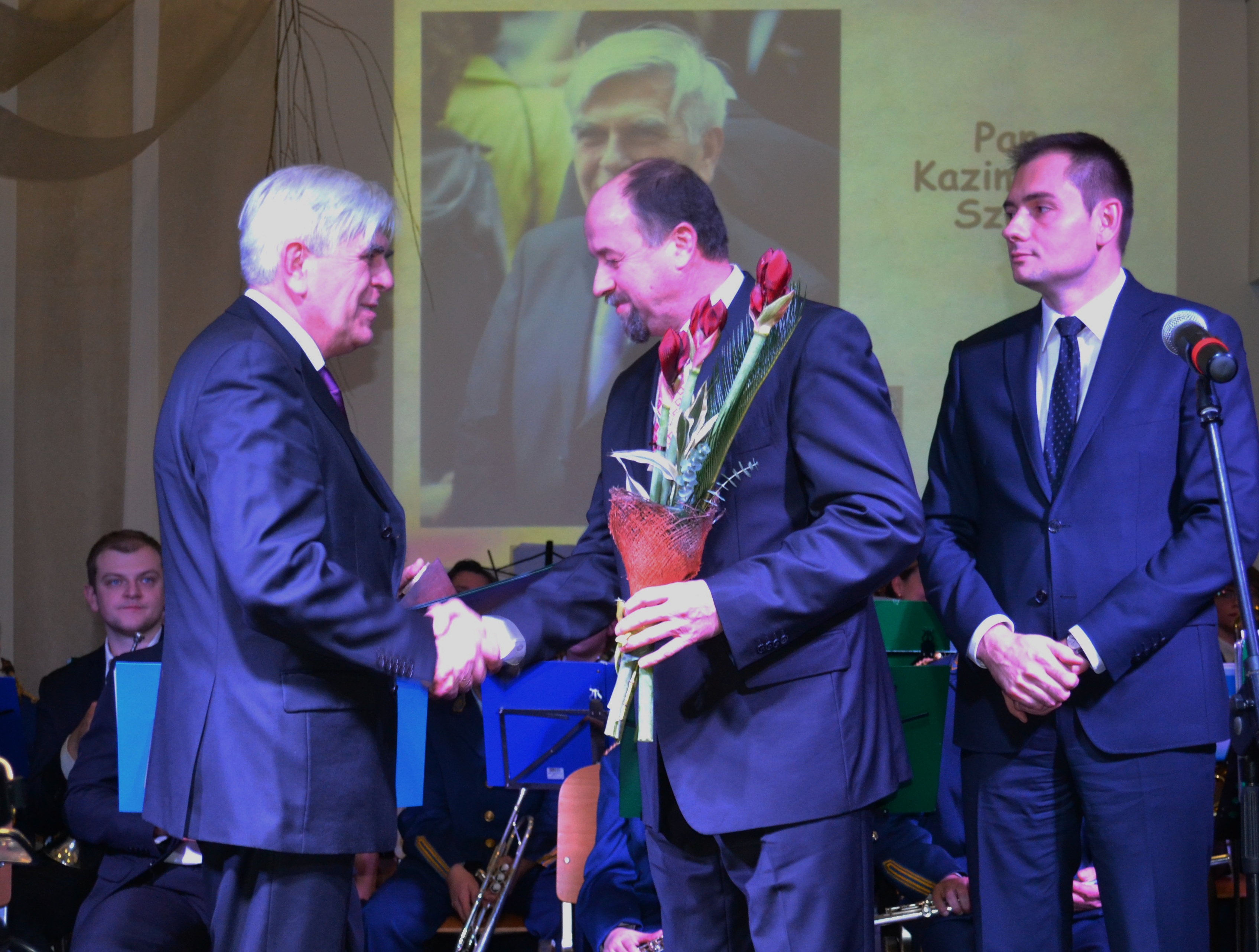 Zdjęcie portretowe Kazimierza Szulca - mężczyzny z&nbsp;siwymi włosami, ubranego w&nbsp;ciemną marynarkę, białą koszulę i&nbsp;niebieski krawat.