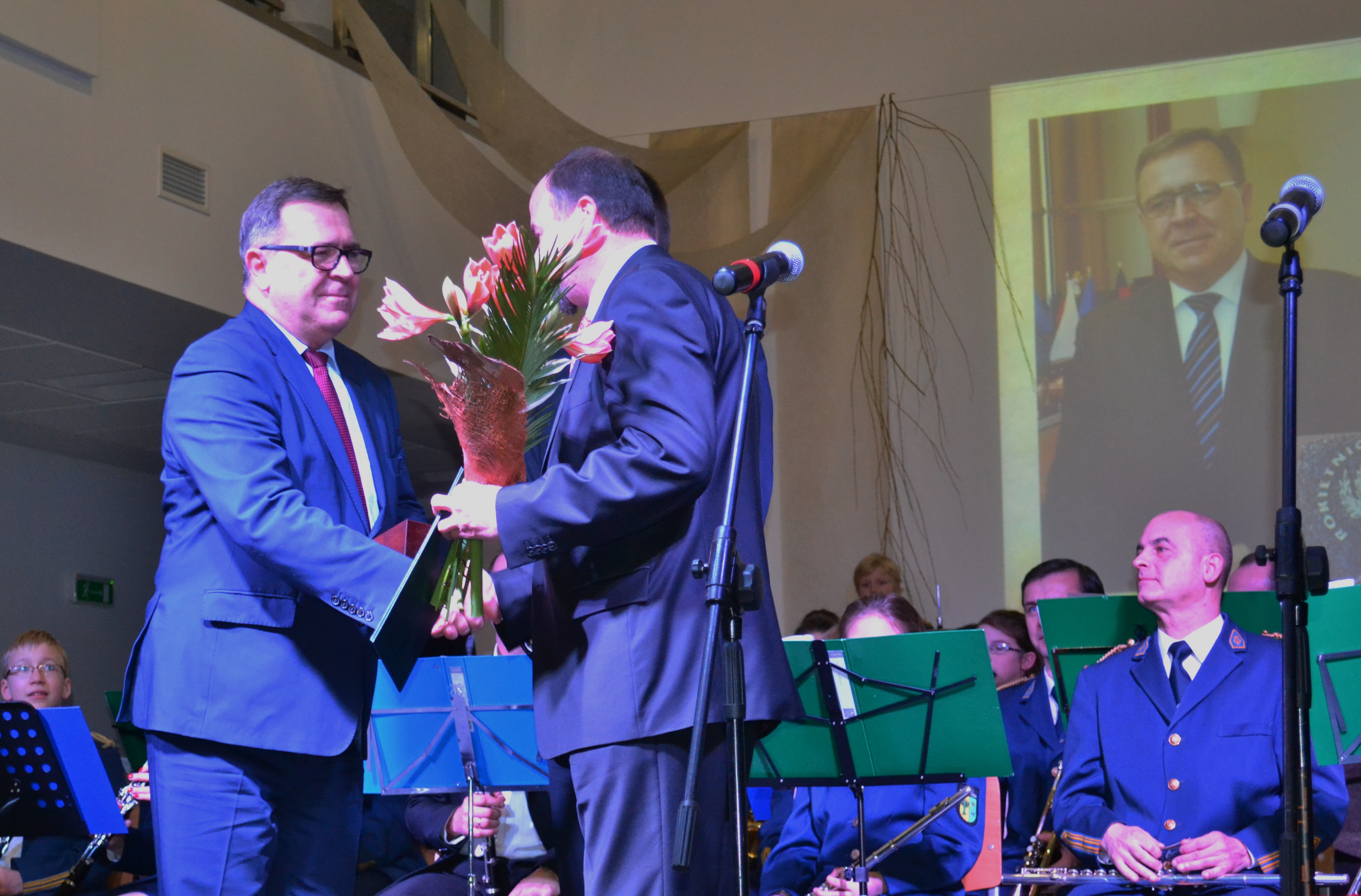 Na zdjęciu Jan Grabkowski w&nbsp;ciemnym garniturze, białej koszuli i&nbsp;krawacie w&nbsp;paski. Za nim puchar i&nbsp;proporczyki z&nbsp;flagą Polski i&nbsp;Unii Europejskiej.
