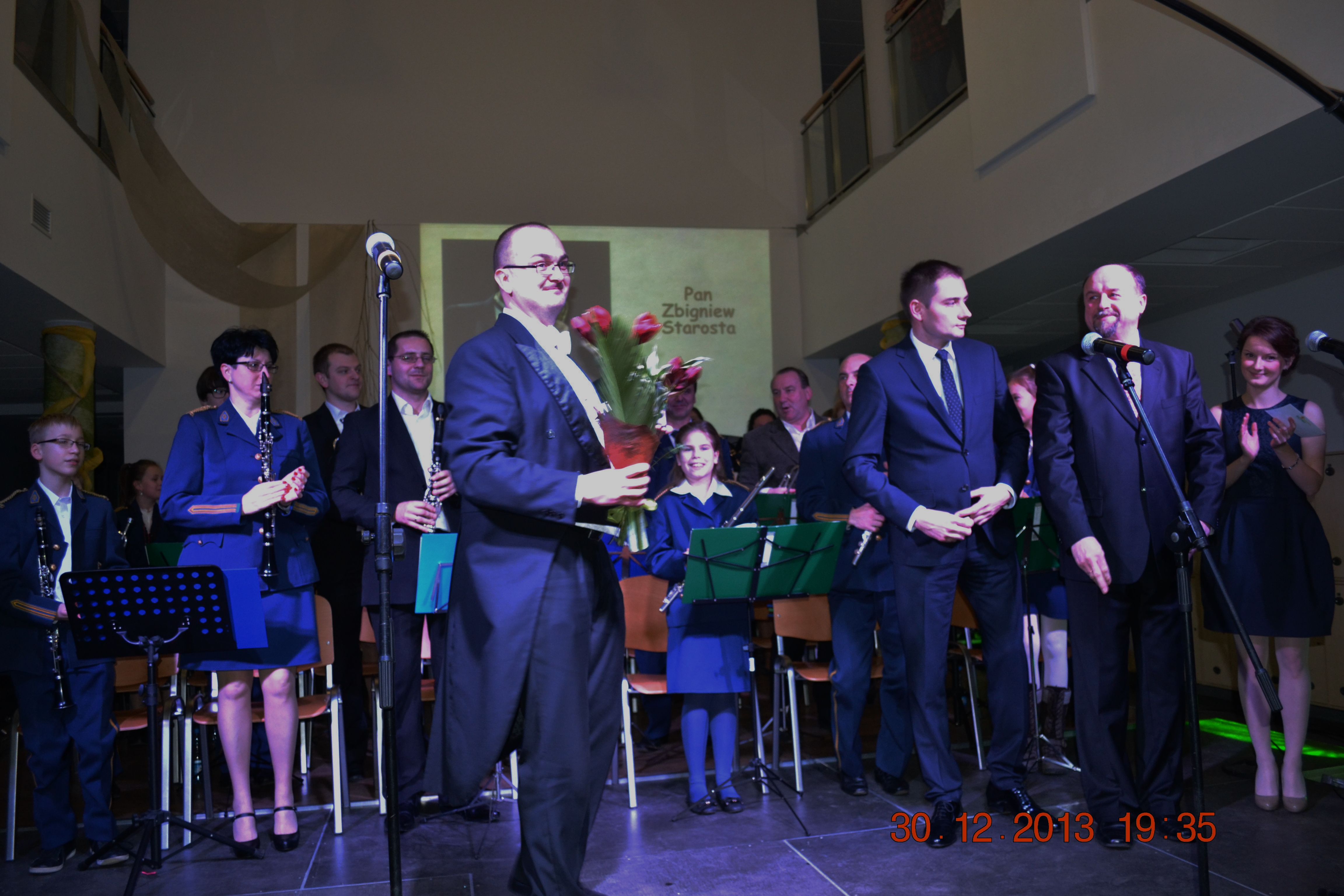 Na zdjęciu Zbigniew Starosta w&nbsp;ciemnym garniturze grający na&nbsp;puzonie. Za nim na&nbsp;scenie muzycy, przed nimi pulpity.