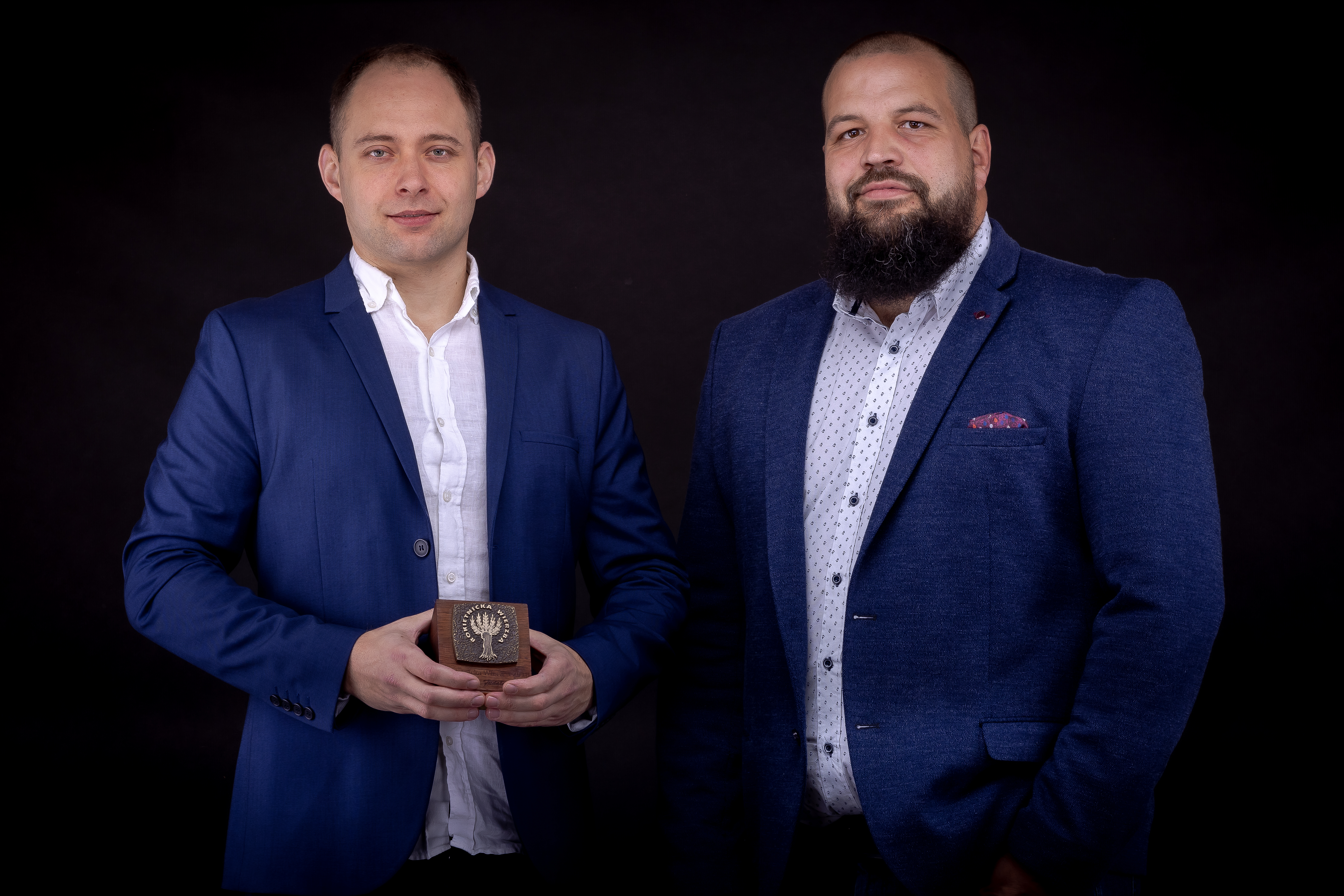 Na zdjęciu laureaci statuetki Rokietnickiej Wierzby 2021, od lewej Michał Siemiński i&nbsp;Marcin Redzyński na&nbsp;czarnym tle. Obaj w&nbsp;granatowych, rozpiętych marynarkach i&nbsp;jasnych koszulach. Pierwszy trzyma w&nbsp;rękach statuetkę Rokietnickiej Wierzby.
